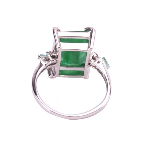85 - An 18-carat white gold and emerald ring; emerald cut within four claw corner mounts, the shoulders s... 