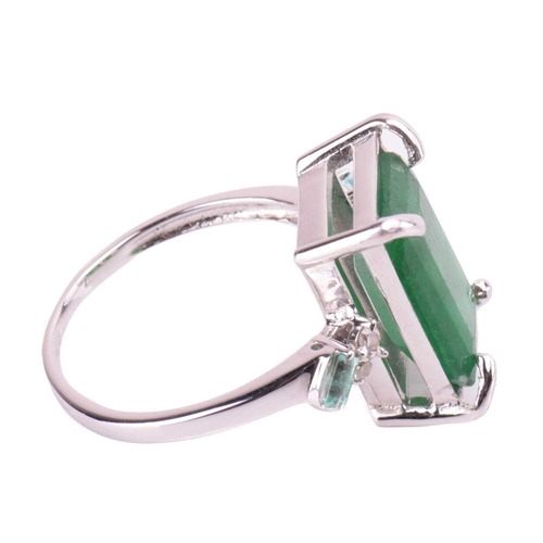 85 - An 18-carat white gold and emerald ring; emerald cut within four claw corner mounts, the shoulders s... 