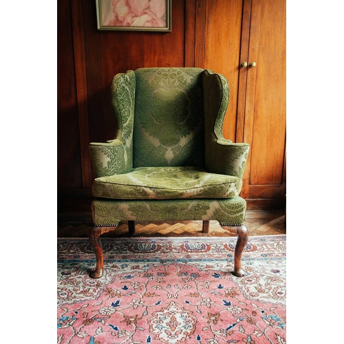 125 - A George II green-upholstered wing armchair, on walnut cabriole legs, old repairs, 111 cm high x 77 ... 