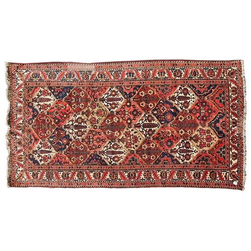 165 - A red ground Baktiari carpet, with an allover compartmented design within multiple borders, 302 cm x... 