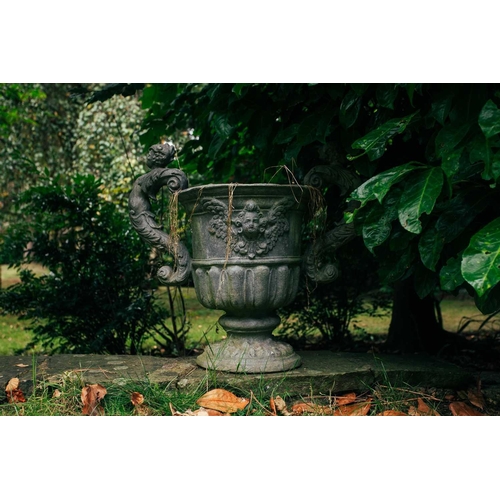 185 - A set of four twin-handled lead garden urns, in the form of vases with winged mask sides above reedi... 