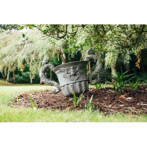 185 - A set of four twin-handled lead garden urns, in the form of vases with winged mask sides above reedi... 