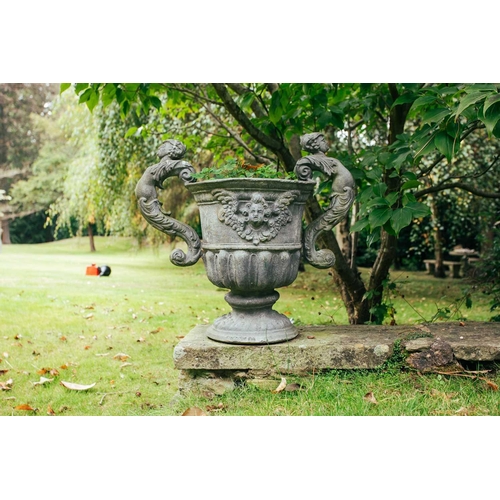 185 - A set of four twin-handled lead garden urns, in the form of vases with winged mask sides above reedi... 