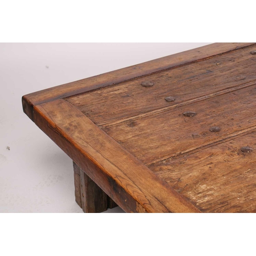 294 - A large coffee table, constructed from a vintage door with metal studs, on bold square section timbe... 