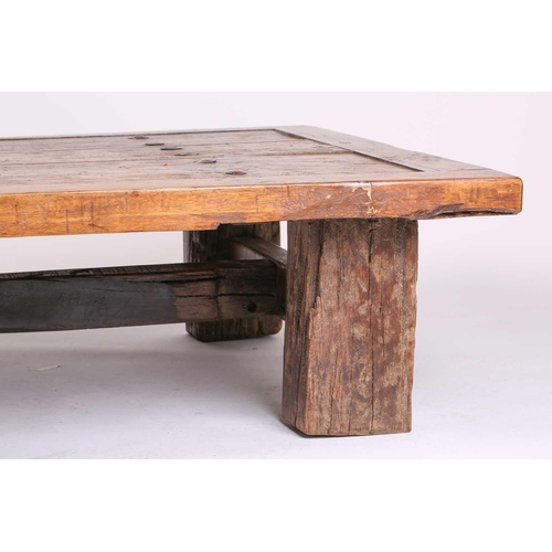 294 - A large coffee table, constructed from a vintage door with metal studs, on bold square section timbe... 