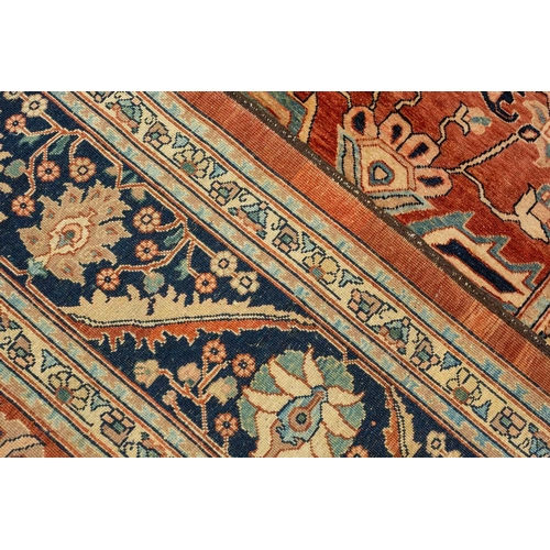 298 - A large brick red ground Serapi-style carpet with central boss and geometric flowers and shrubs, wit... 