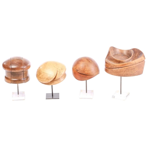 371 - Four hardwood vintage hat lasts, of varying shapes, on display stands, tallest 34.5 cm on the stand ... 