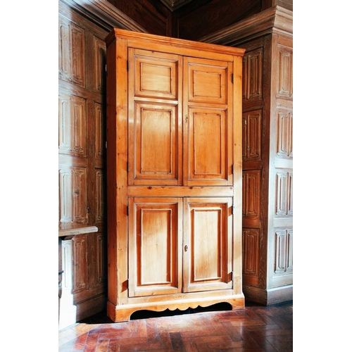 64 - An early 19th century pine corner cupboard, with pair of panelled doors above another similar pair, ... 