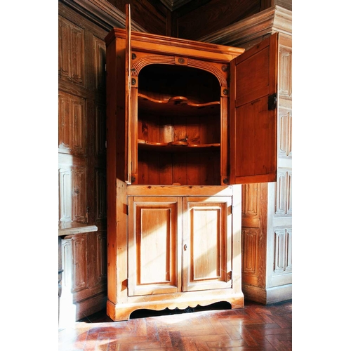 64 - An early 19th century pine corner cupboard, with pair of panelled doors above another similar pair, ... 