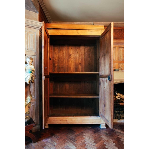 65 - A 19th century Continental maple armoire, the moulded cornice over a pair of panelled doors, on moul... 