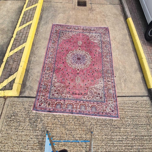 91 - An old pastel pink ground possibly Turkish carpet with a central boss with hanging lanterns within w... 