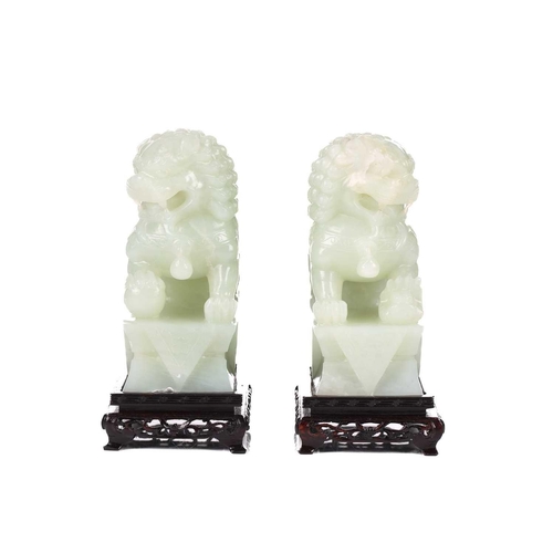 118 - A pair of Chinese bowenite carved dogs of foo, each on a conforming wooden display stand, each 20 cm... 