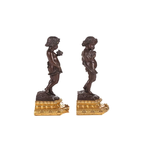 244 - A pair of bronze figures of standing putti holding a dove and a nest, on ormolu cabochon design socl... 