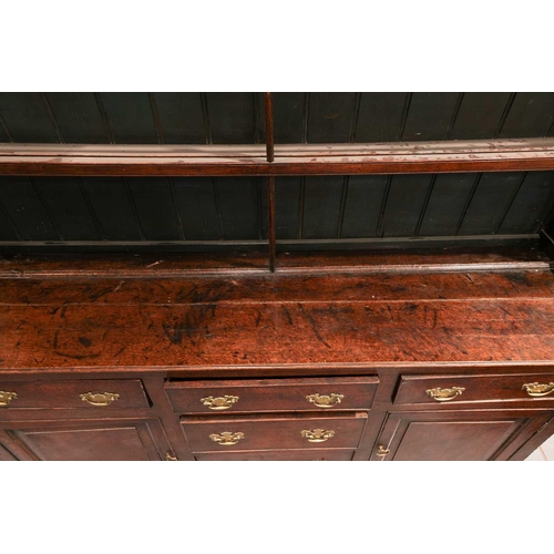 166 - A George III oak cupboard dresser and Delft rack, the base with a central bank of drawers flanked by... 