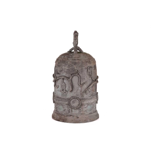 68 - An archaistic Chinese bronze bell with a rustic loop handle the domed body with raised flowering ten... 