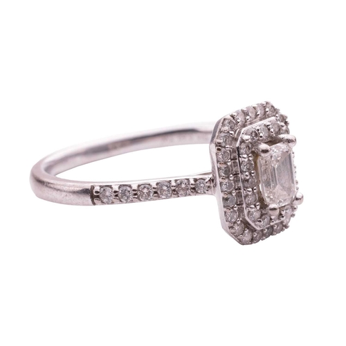 111 - A diamond cluster ring, featuring an emerald cut diamond within a two row border of round brilliant ... 