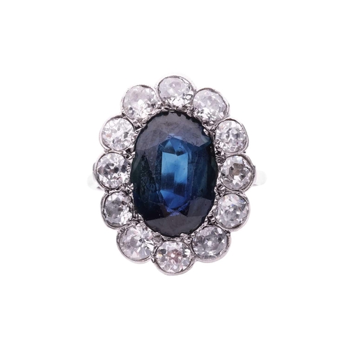 113 - A sapphire and diamond cluster ring, circa 1920s, featuring an oval green-blue sapphire measuring 12... 