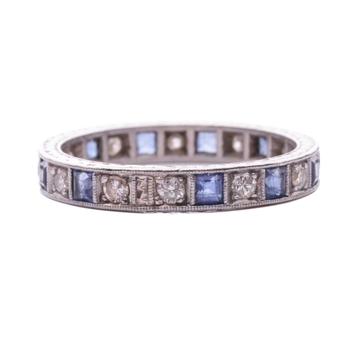 128 - A sapphire and diamond eternity ring, alternating with square table-cut sapphires and transitional-c... 