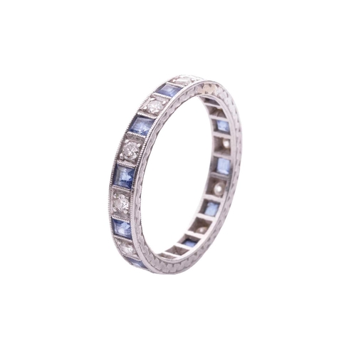 128 - A sapphire and diamond eternity ring, alternating with square table-cut sapphires and transitional-c... 