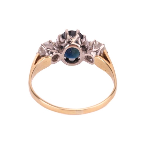 179 - A sapphire and diamond three-stone ring, centred with an oval-cut sapphire in dark greenish-blue col... 