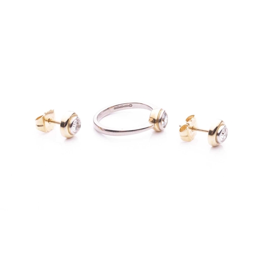 181 - A diamond solitaire ring in 18ct bi-coloured gold and a pair of stud earrings; the ring is centred w... 