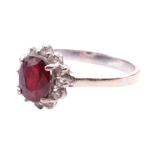 196 - A ruby and diamond cluster ring, the oval mixed-cut ruby of deep brownish-red colour and measuring a... 