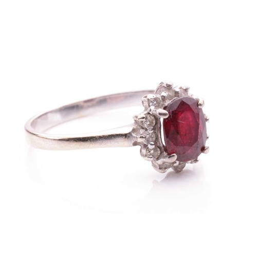 196 - A ruby and diamond cluster ring, the oval mixed-cut ruby of deep brownish-red colour and measuring a... 