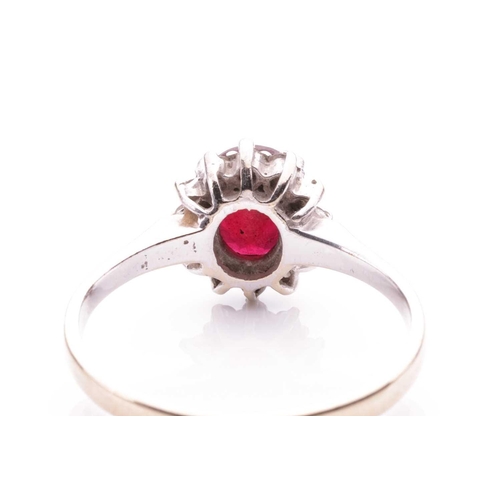 196 - A ruby and diamond cluster ring, the oval mixed-cut ruby of deep brownish-red colour and measuring a... 