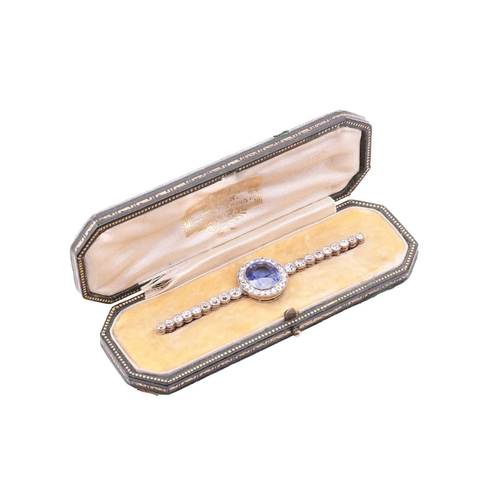 201 - An Art Deco sapphire and diamond set bar brooch, featuring a mixed oval cut sapphire of bright blue ... 