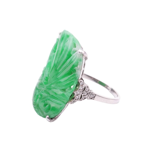 206 - An Art Deco carved jadeite dress ring, circa 1900s, the cushion-shaped jade panel depicting a Chines... 