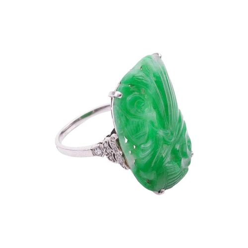 206 - An Art Deco carved jadeite dress ring, circa 1900s, the cushion-shaped jade panel depicting a Chines... 