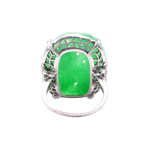 206 - An Art Deco carved jadeite dress ring, circa 1900s, the cushion-shaped jade panel depicting a Chines... 