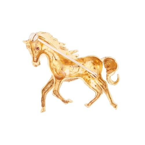 66 - A horse brooch, sculpted as a galloping horse with textured details and ruby-set eyes, brooch fittin... 