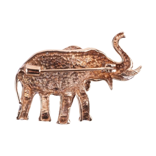 68 - A gem-set elephant brooch in 9ct gold, sculpted as an elephant in caparison, textured and adorned wi... 