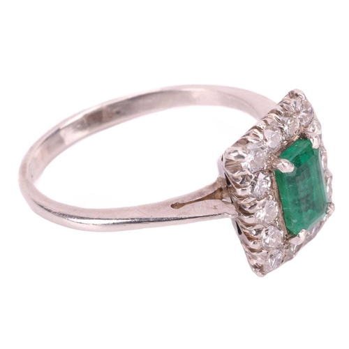 83 - An emerald and diamond halo ring, centred with an octagonal step-cut emerald of 6.4 x 4.1 x 3.7 mm, ... 