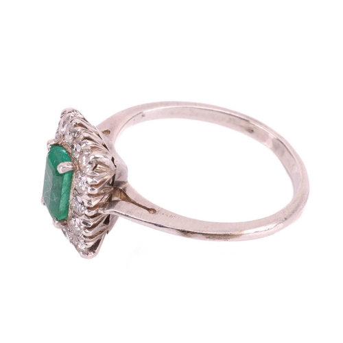 83 - An emerald and diamond halo ring, centred with an octagonal step-cut emerald of 6.4 x 4.1 x 3.7 mm, ... 