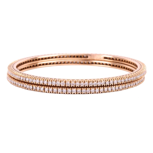 91 - A pair of diamond bangles, each set with a single row of round brilliant cut diamonds, with an inner... 