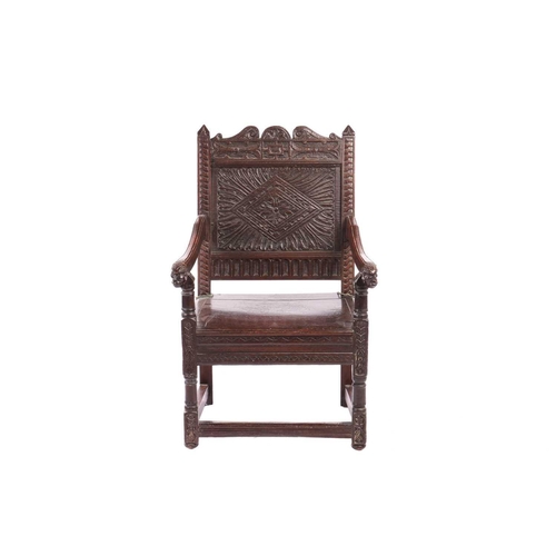 119 - An oak wainscot armchair, 17th century and later, with carved decoration, the arms terminating in ca... 