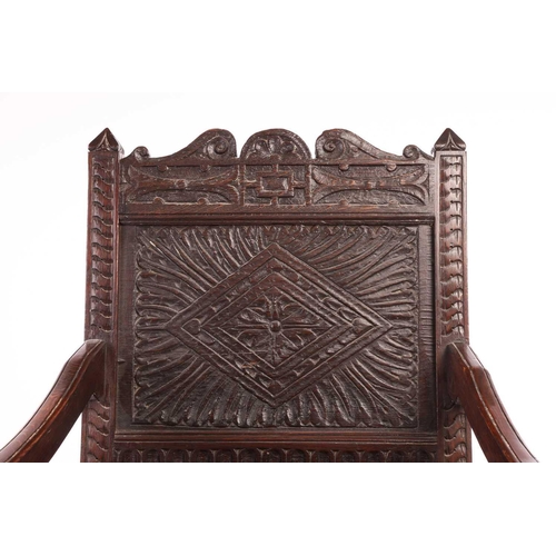 119 - An oak wainscot armchair, 17th century and later, with carved decoration, the arms terminating in ca... 