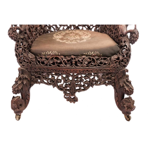 129 - A Bombay Presidency carved rosewood arched back armchair, C1860s profusely carved with Indian strawb... 