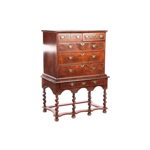 136 - A 17th-century and later figured walnut chest on stand, the upper section with quarter veneered top ... 