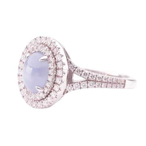 100 - A star sapphire and diamond cluster ring in 18ct white gold, centred with an oval star sapphire cabo... 