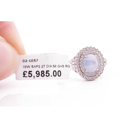 100 - A star sapphire and diamond cluster ring in 18ct white gold, centred with an oval star sapphire cabo... 