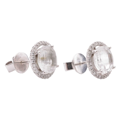 104 - A pair of topaz and diamond halo stud earrings, each composed with a round chequerboard-cut white to... 