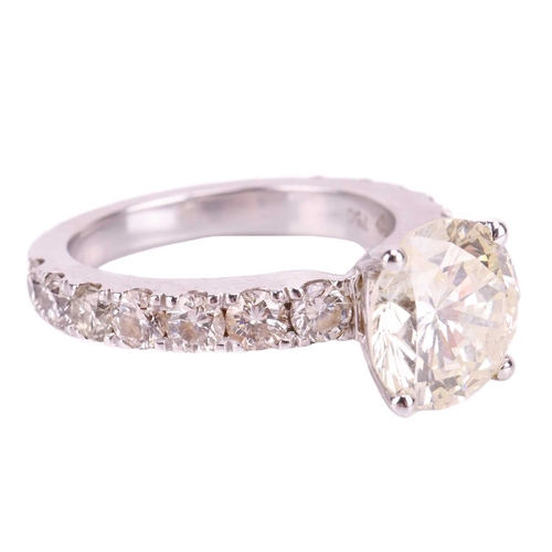 135 - A diamond solitaire ring with diamond set shoulders, featuring a round brilliant cut diamond with an... 