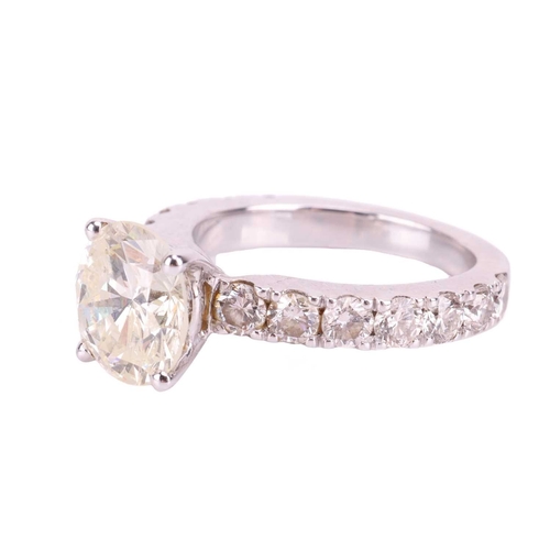 135 - A diamond solitaire ring with diamond set shoulders, featuring a round brilliant cut diamond with an... 