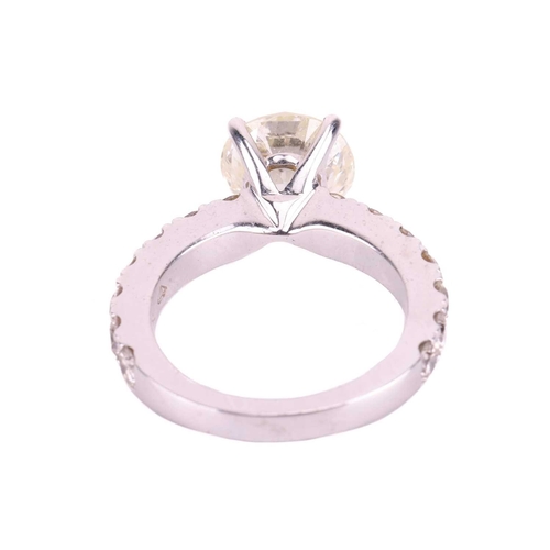 135 - A diamond solitaire ring with diamond set shoulders, featuring a round brilliant cut diamond with an... 