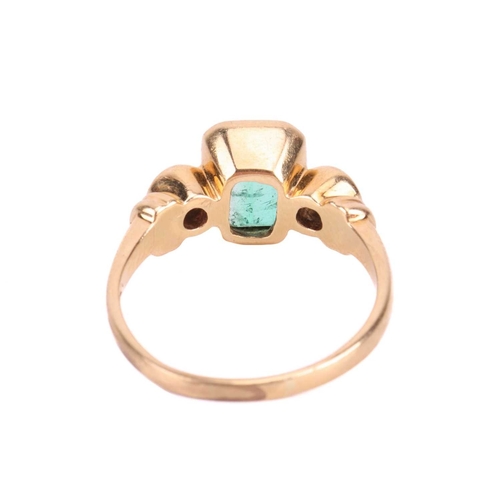 19 - An emerald and diamond three stone ring, set with an emerald measuring 8 x 6 x 3.6mm, flanked by rou... 