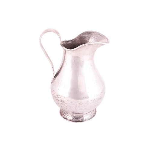 208 - A white metal jug possibly Bolivian of baluster form with a tapered loop handle and flared foot, 23 ... 