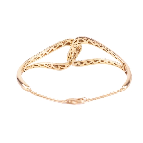 40 - A diamond bangle, in a linked cross-over design set throughout with round brilliant cut champagne di... 